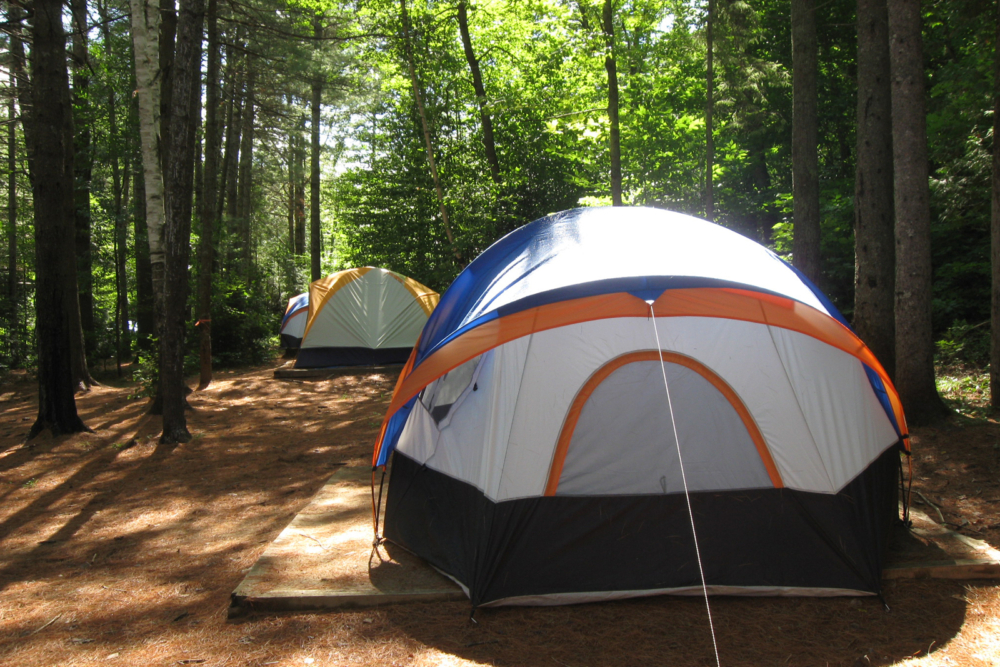 Deux tentes colorées installées dans un boisé, offrant un espace de camping paisible chez Chalets Lanaudière.