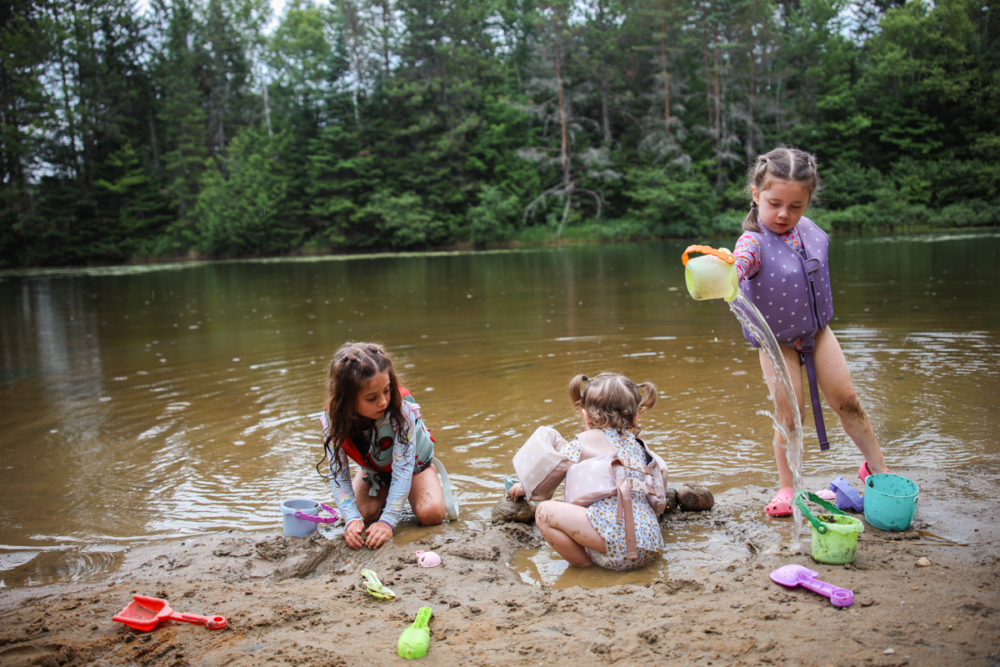 Enfants s’amusant au bord d’un étang avec des jouets, lors d’un séjour en nature aux Chalets Lanaudière.