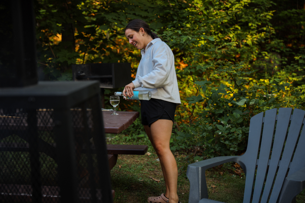 Personne préparant un repas sur la terrasse d’un chalet de Chalets Lanaudière, entourée d’arbres et de verdure.