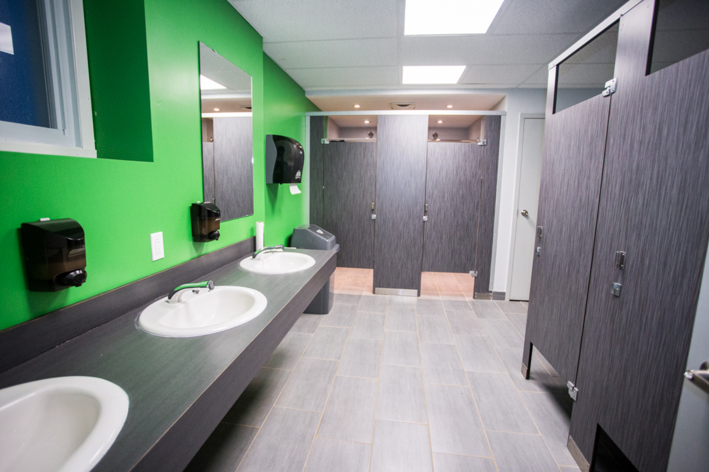Salle de bain moderne d’un terrain de camping, avec lavabos, miroirs et cabines privées.