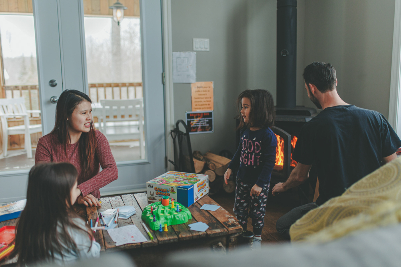 Famille réunie dans un chalet de Chalets Lanaudière autour d’un jeu de société, près du poêle à bois allumé.