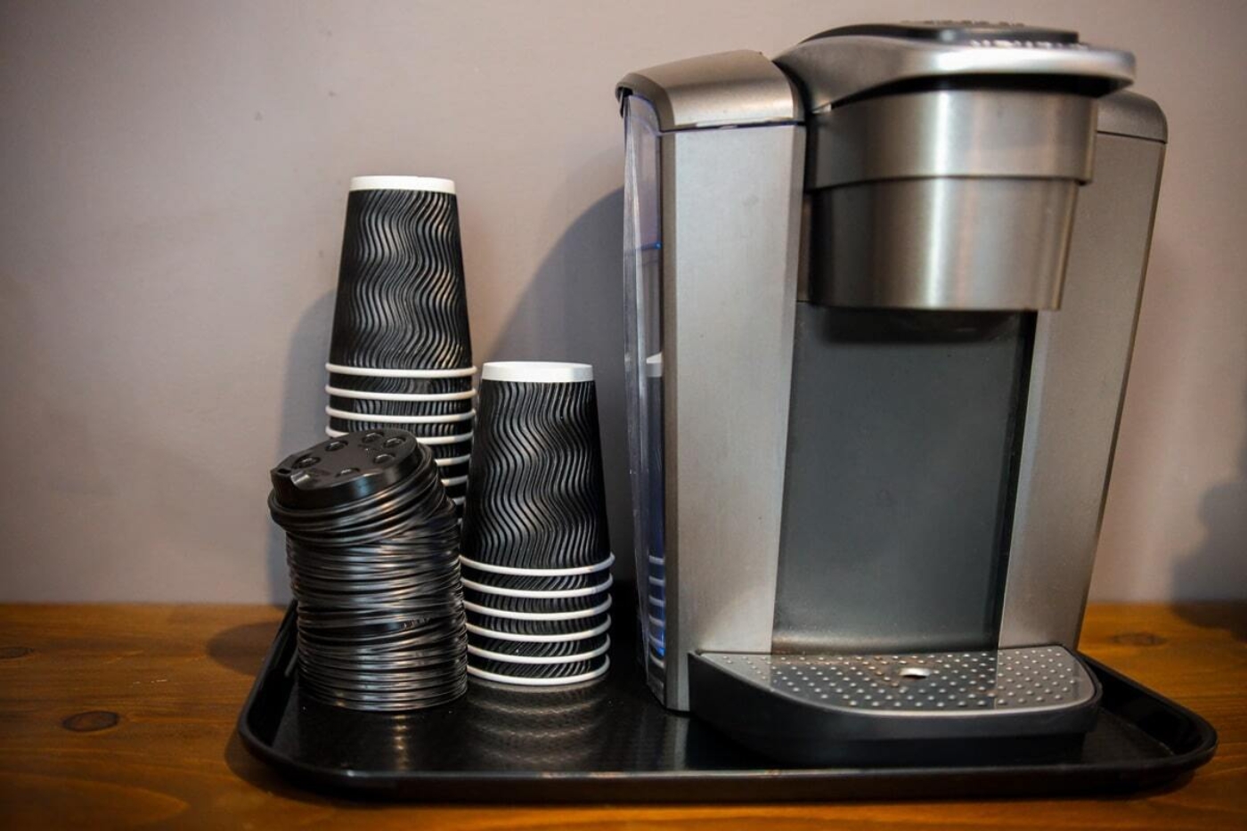 Machine à café avec gobelets jetables empilés sur un plateau, dans une cuisine de chalet des Chalets Lanaudière.
