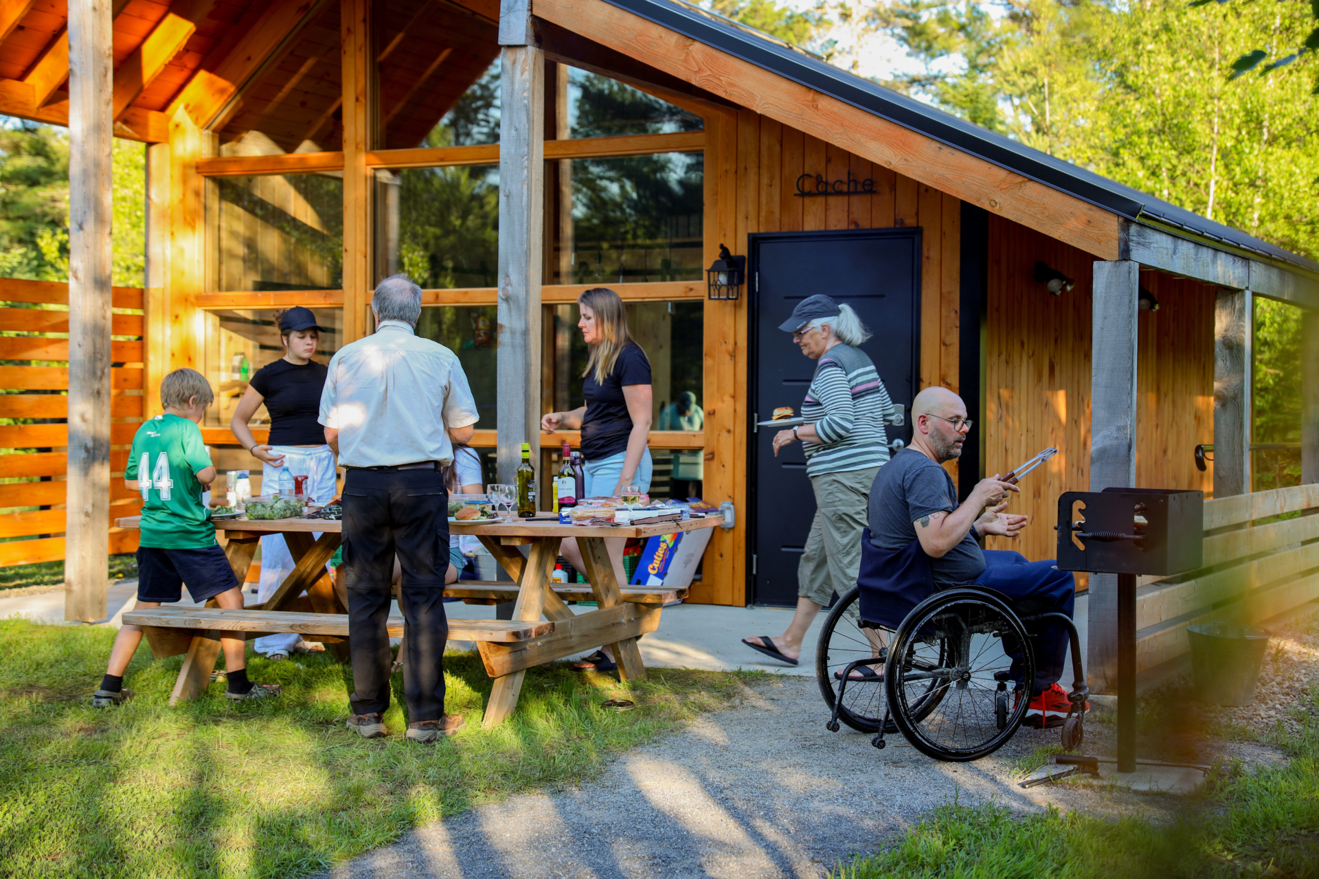 Groupe profitant d’un repas et de la terrasse d’un chalet accessible de Chalets Lanaudière, avec une personne en fauteuil roulant.