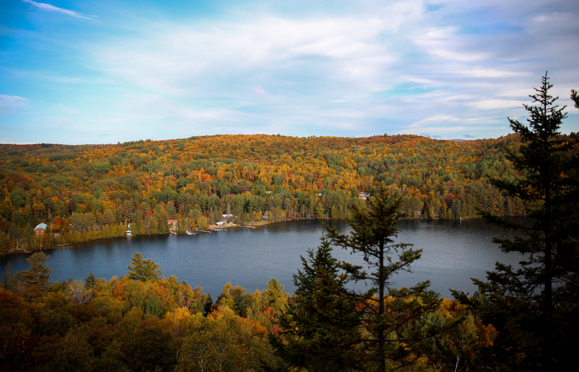 Vue panoramique d’un lac entouré de forêts aux couleurs automnales, près des chalets de Lanaudière.
