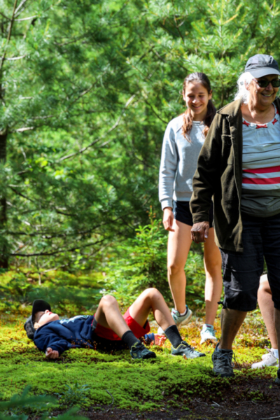 Groupe profitant d’une randonnée en forêt près de leur hébergement aux Chalets Lanaudière, avec une personne se reposant sur la mousse.
