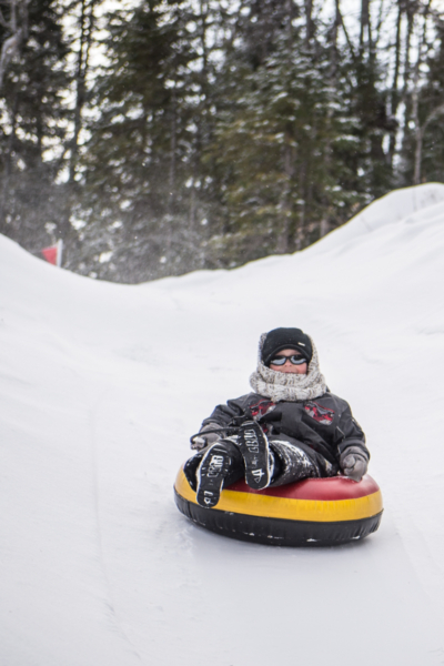 Personne dévalant une pente enneigée en bouée, lors d’une activité hivernale aux Chalets Lanaudière.