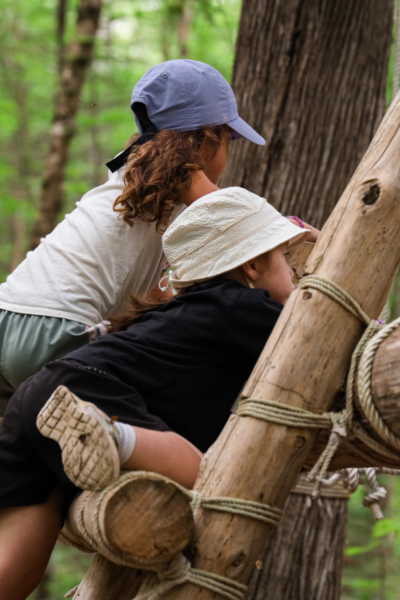 Adulte et enfant s’amusant sur une structure d’escalade en bois dans la forêt, lors d’un séjour aux Chalets Lanaudière.