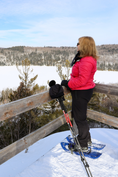 Personne en raquettes admirant le paysage hivernal depuis un belvédère près d’un chalet de Chalets Lanaudière