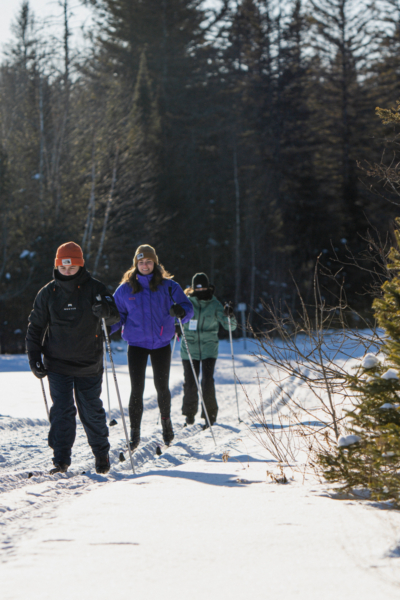 Groupe de personnes faisant de la randonnée en raquettes sur un sentier enneigé près des chalets Lanaudière.