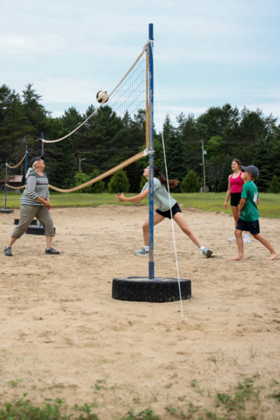 Groupe jouant au volleyball de plage sur un terrain sablonneux de Chalets Lanaudière.
