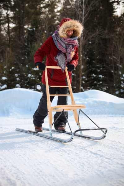 Person pratiquant la trottinette des neiges sur un sentier enneigé près d’un chalet de Chalets Lanaudière.