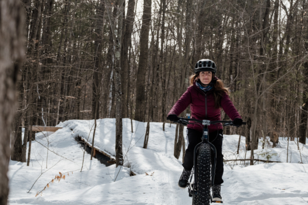 Personne faisant du vélo à pneus surdimensionnés dans un sentier forestier enneigé près des chalets Lanaudière.