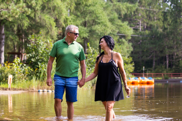 Couple profitant d’une promenade dans l’eau près d’un chalet de Chalets Lanaudière, avec des pédalos colorés en arrière-plan.