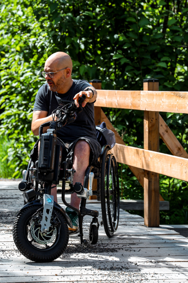 Personne en fauteuil roulant motorisé profitant d’une promenade en plein air près d’un chalet de Chalets Lanaudière.