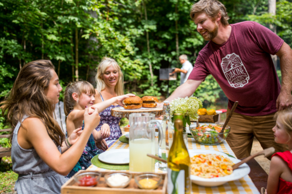 Famille profitant d’un repas convivial en plein air lors d’un séjour en chalet de Chalets Lanaudière.