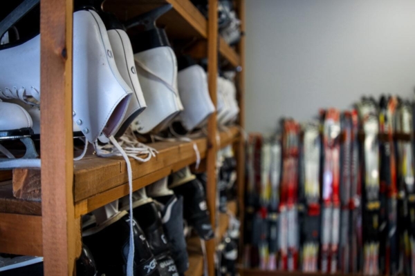 Rangement d’équipement de ski avec bottes sur étagères et skis alignés, dans une installation de Chalets Lanaudière.