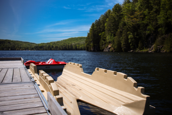 Pédalo et canot rouge amarrés à un quai sur un lac entouré de forêt, près des chalets Lanaudière.