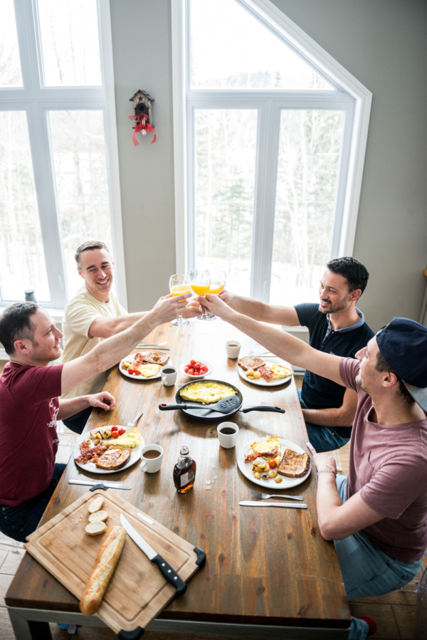 Groupe d’amis partageant un repas et trinquant dans un chalet lumineux de Chalets Lanaudière.