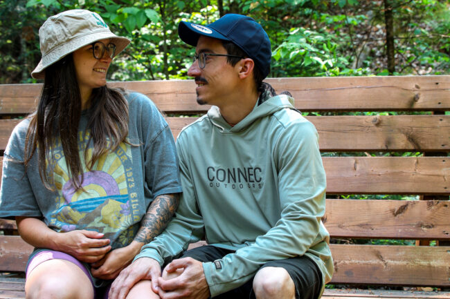 Couple souriant assis sur un banc en bois au cœur de la nature lors d’un séjour chez Chalets Lanaudière.