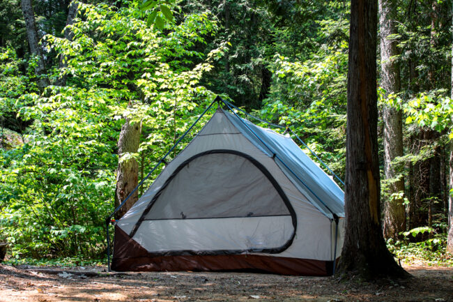 Tente installée dans un boisé, offrant une expérience de camping en pleine nature près des chalets Lanaudière.