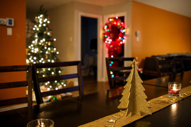 Intérieur chaleureux d’un chalet de Chalets Lanaudière décoré pour Noël, avec sapin illuminé et centre de table en forme de sapin doré.