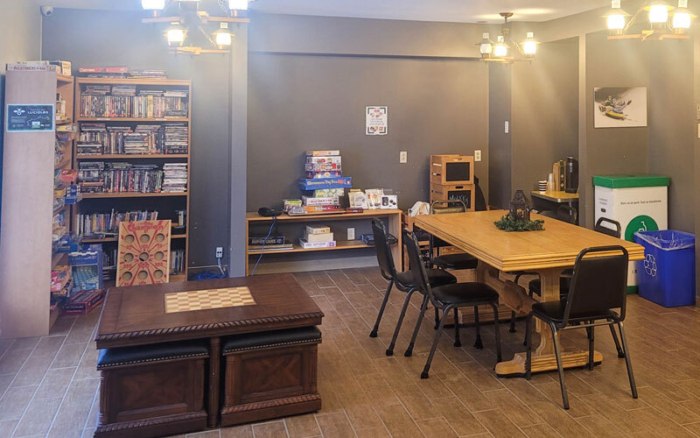 Salle de jeux d’un chalet, avec grande table, jeux de société, bibliothèque, téléviseur et coin détente.