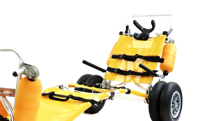 Fauteuil roulant tout-terrain jaune, adapté aux déplacements sur la plage et offert comme équipement accessible aux vacanciers.
