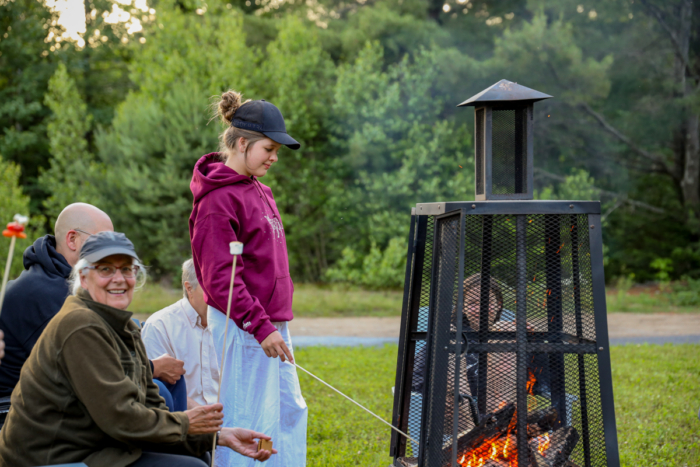 Famille réunie autour d’un foyer extérieur grillagé dans un camping de Chalets Lanaudière.
