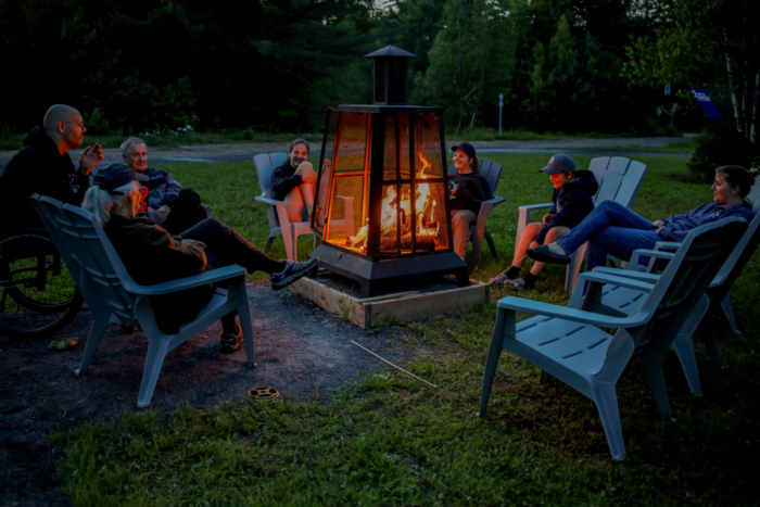 Groupe profitant d’un feu extérieur en soirée dans un espace de camping des Chalets Lanaudière.