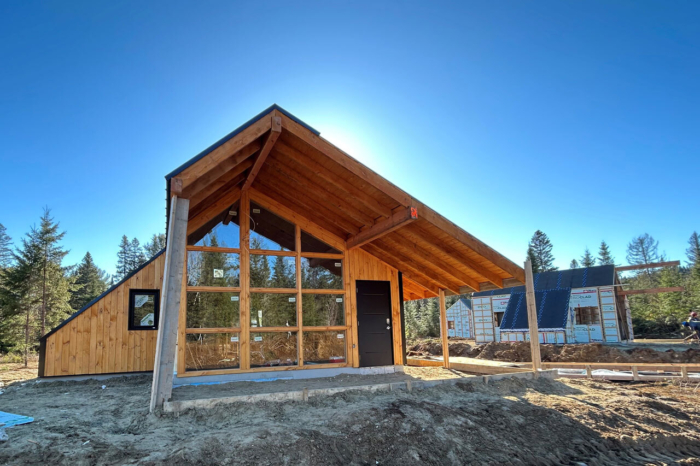 Chalet en bois de Chalets Lanaudière, avec grande fenestration, toit en pente et terrain forestier sous un ciel bleu.