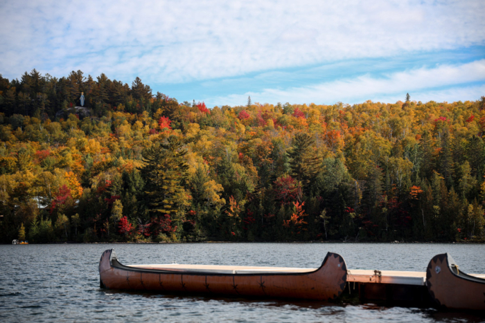 Canot sur un lac bordé d’une forêt aux couleurs automnales, près des chalets de Chalets Lanaudière