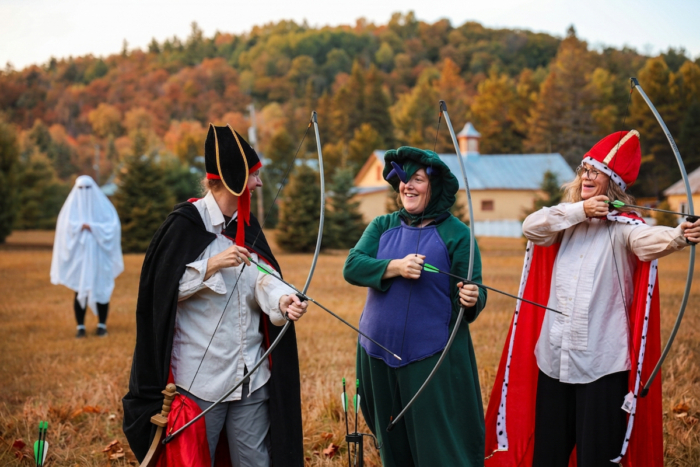 Groupe de personnes en costumes médiévaux s’amusant au tir à l’arc dans un décor automnal près des chalets Lanaudière.