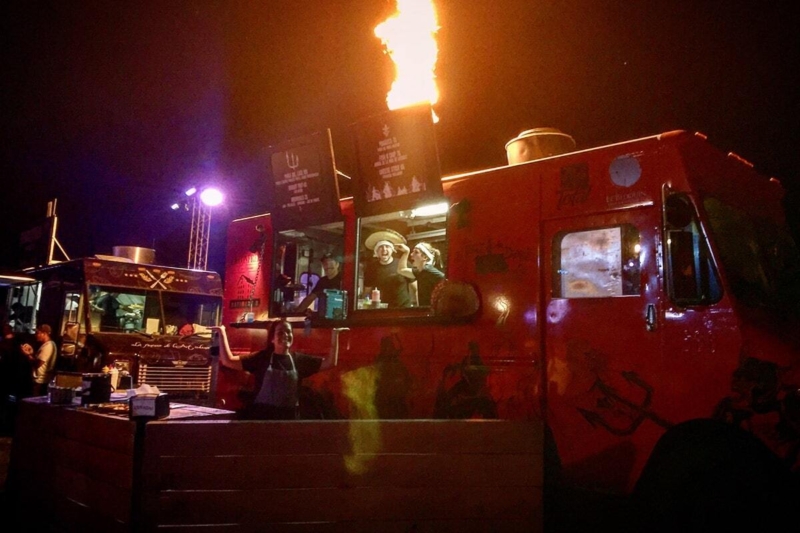Camions-restaurants illuminés la nuit, offrant des repas lors d’un événement.