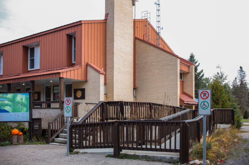 Entrée accessible d’un établissement de Chalets Lanaudière avec rampe d’accès, panneaux d’interdiction de stationnement et environnement boisé.