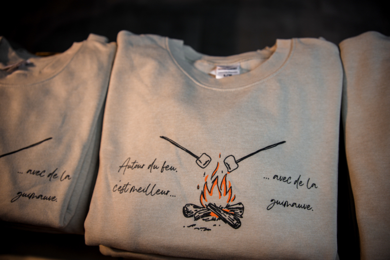 Chandails de Chalets Lanaudière illustrés d’un feu de camp et portant l’inscription « Autour du feu, c’est meilleur… avec de la guimauve ».