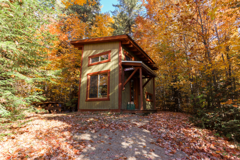 Petite cabane de camping de Chalets Lanaudière entourée d’arbres aux couleurs automnales.