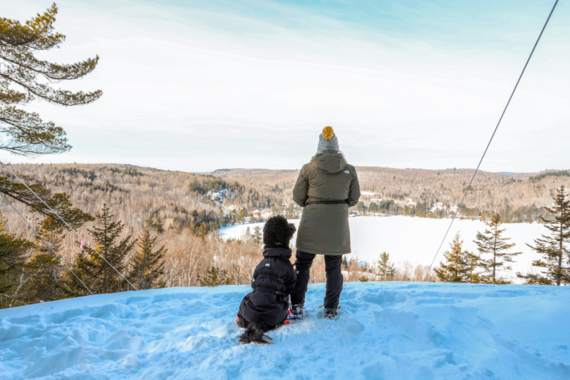 Parent et enfant admirant un paysage hivernal enneigé depuis un chalet de Chalets Lanaudière.