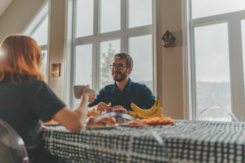 Couple partageant un repas dans la salle à manger lumineuse d’un chalet de Chalets Lanaudière.