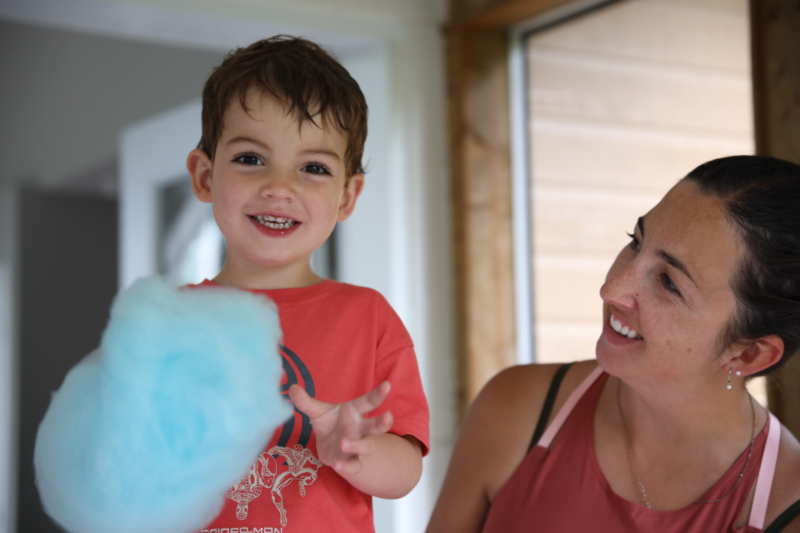 Enfant souriant tenant une barbe à papa bleue, accompagné d’un adulte dans un chalet de Chalets Lanaudière.