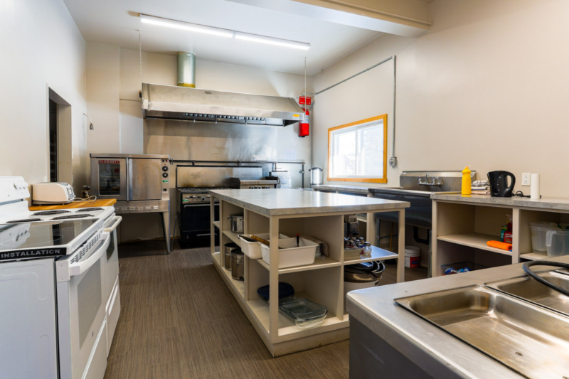 Cuisine professionnelle bien équipée dans un chalet de Chalets Lanaudière, avec appareils en acier inoxydable et grands comptoirs de préparation.