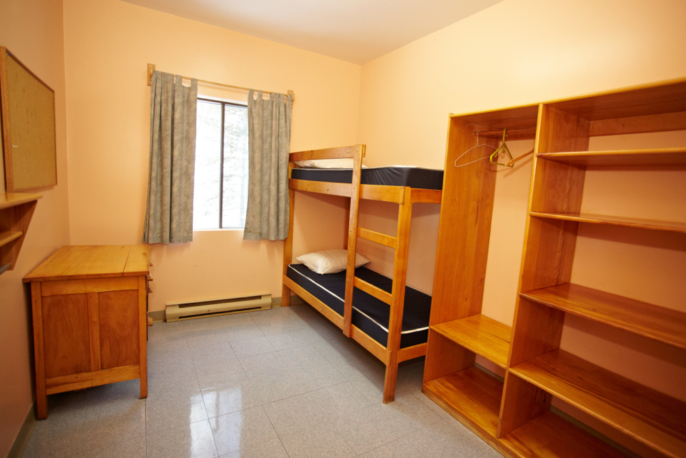 Chambre de chalet avec lits superposés, commode et grand rangement en bois.