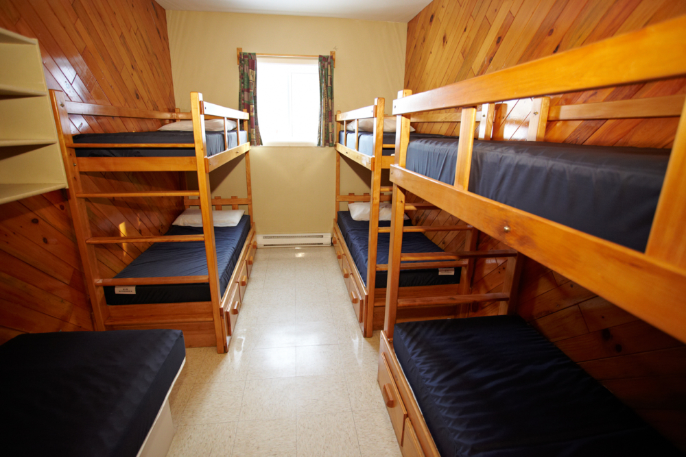 Chambre de chalet avec plusieurs lits superposés en bois, idéale pour accueillir une famille ou un groupe.