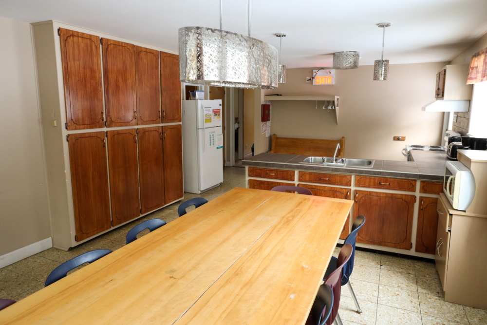 Cuisine spacieuse d’un chalet, avec grande table en bois, armoires rustiques et îlot central entièrement équipé.