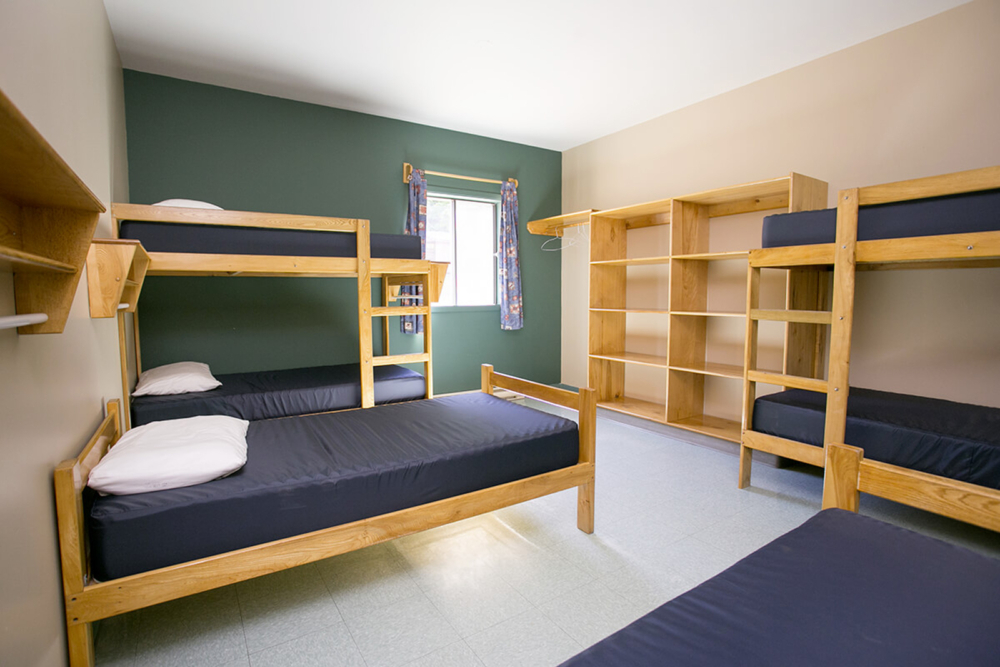 Chambre de chalet avec lits superposés en bois et étagères intégrées.