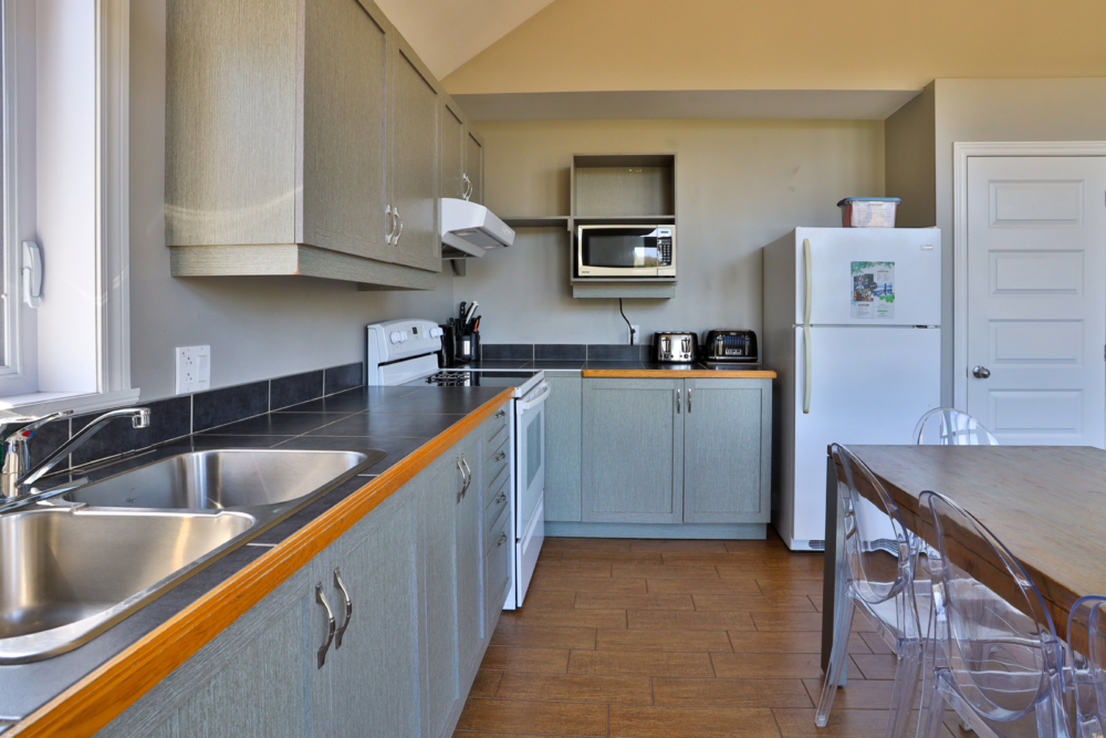 Cuisine entièrement équipée d’un chalet, avec réfrigérateur, cuisinière, micro-ondes, évier double et comptoir-repas.