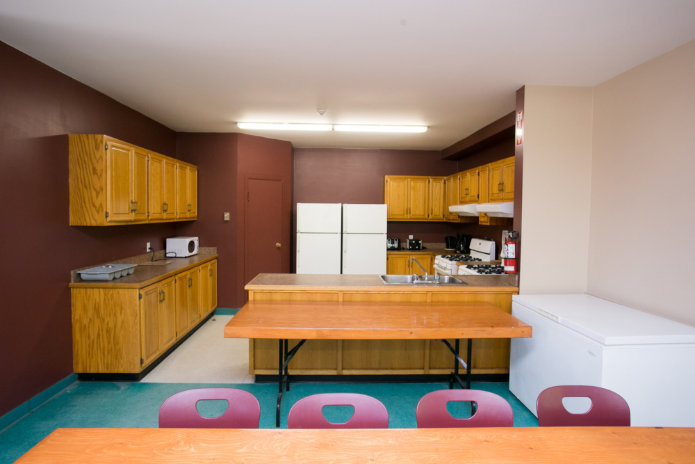 Cuisine entièrement équipée d’un chalet avec comptoir central, réfrigérateur, cuisinière et table à manger.