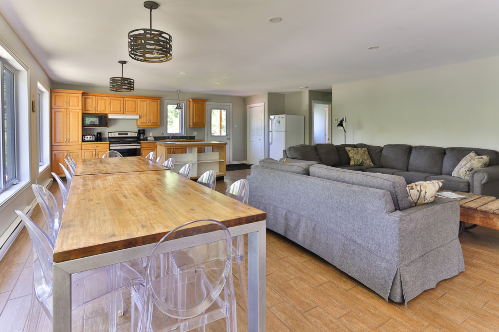 Intérieur lumineux d’un chalet avec grande table à manger, cuisine équipée et salon spacieux.