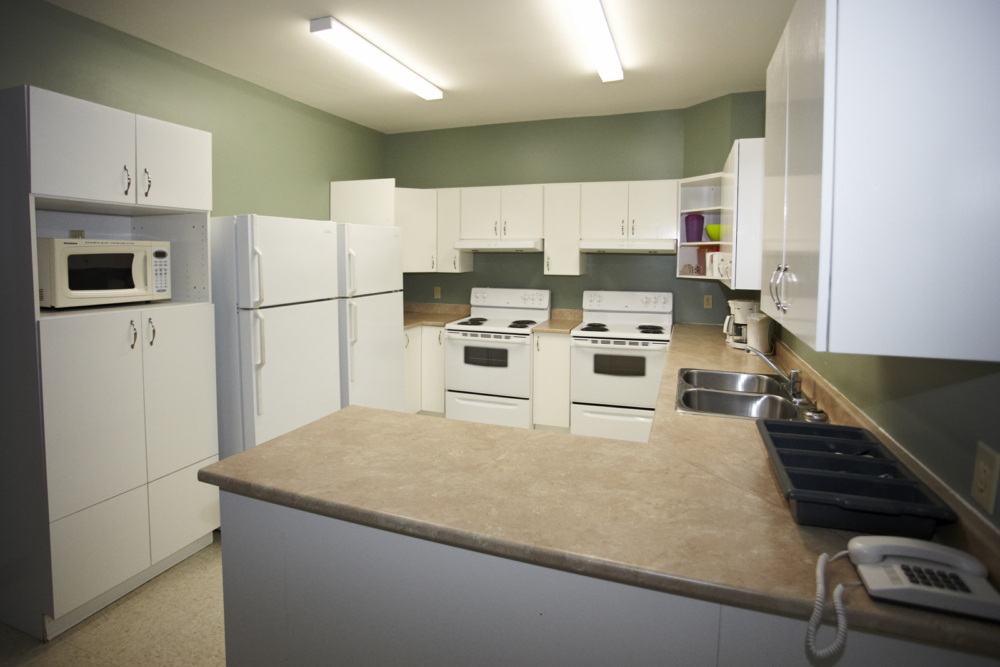 Cuisine spacieuse équipée d’un chalet avec îlot central, électroménagers blancs et doubles éviers.