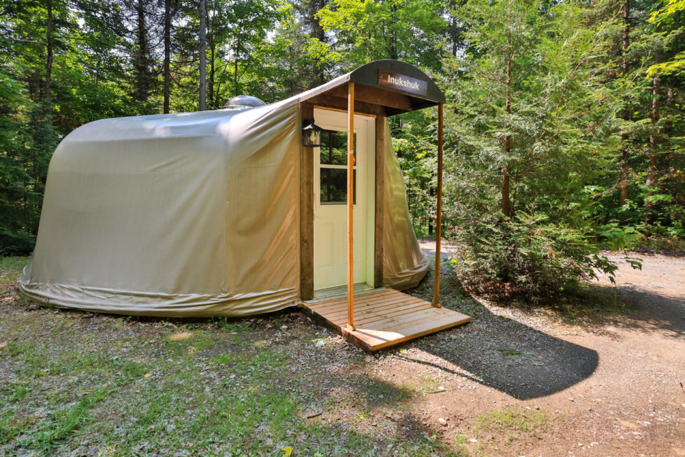 Yourte au cœur de la forêt, avec terrasse en bois.