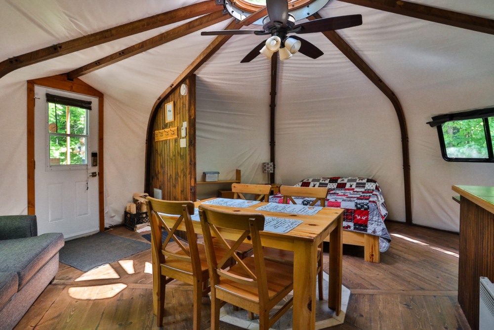 Intérieur chaleureux d’une yourte avec table à manger, divan et lit.